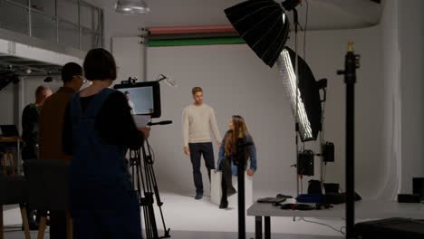 Female-Assistant-Uses-Clapperboard-As-Actors-Shoot-Movie-Or-Video-In-Studio-With-Film-Crew-And-Director-Shot-In-Real-Time-1